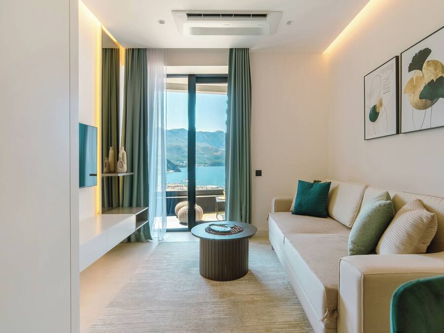 A modern living room with a sofa, a coffee table, and a view of the outdoors.