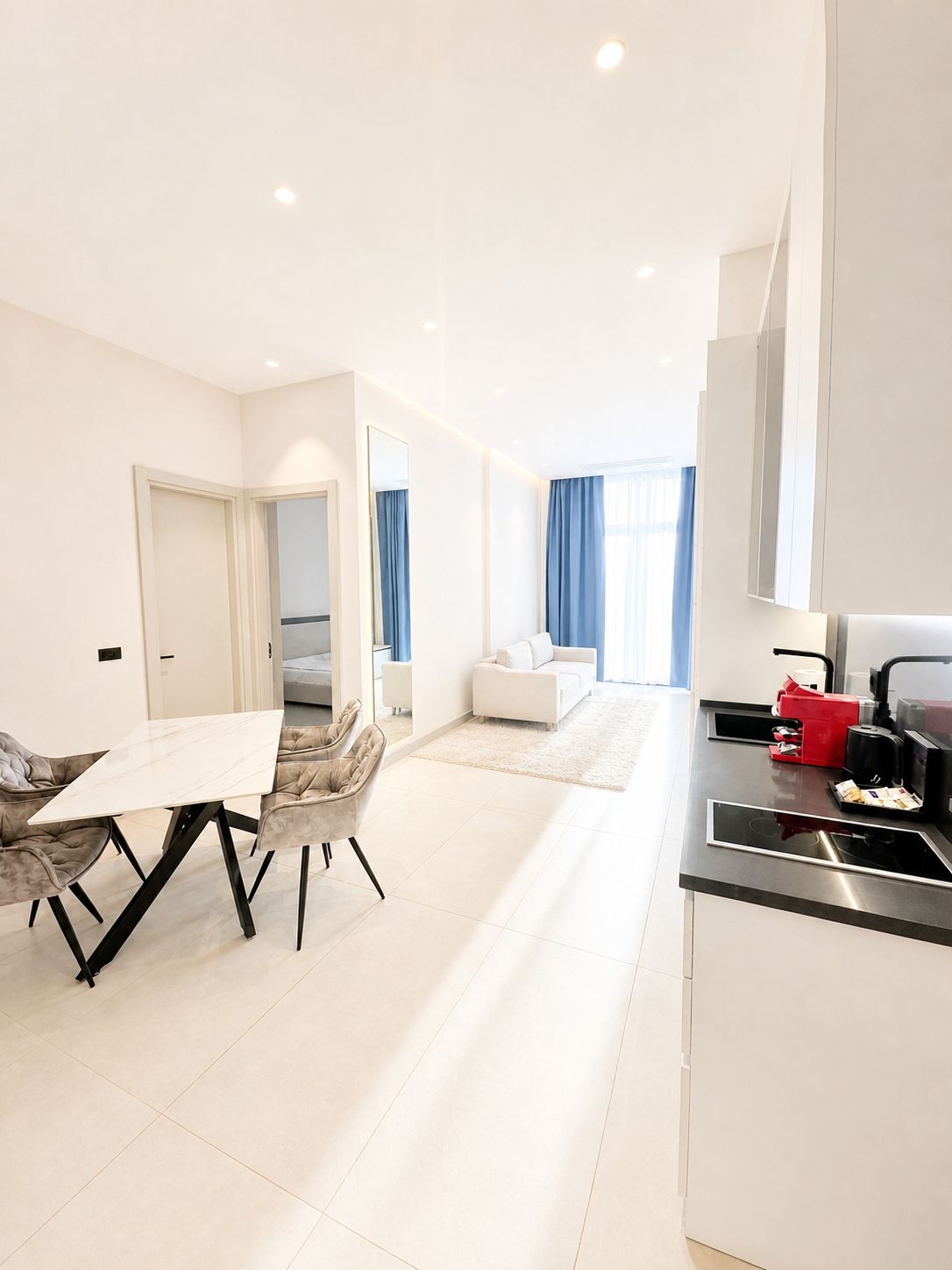 A modern apartment with a dining area, a kitchen, and a living room.