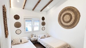 Un dormitorio con dos camas, una ventana y techo de madera.