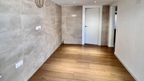 Un pasillo amplio con suelo de madera y un reloj en la pared.