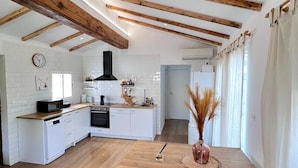 Una cocina moderna con armarios blancos, vigas de madera y una isla central.