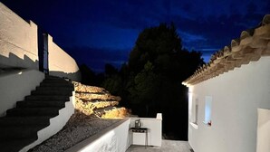 Un patio al aire libre cubierto con suelo de piedra, un pequeño espacio de estar y una escalera que conduce a un edificio.