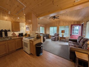 Cozy cabin interior with a fully equipped kitchen, comfortable seating area, and large windows.