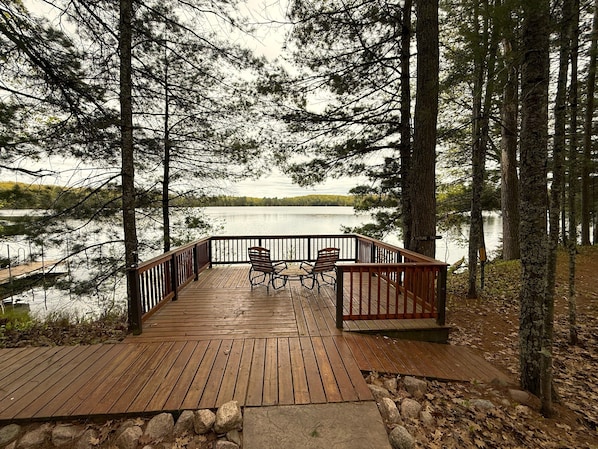 Relax on the deck overlooking the serene lake, surrounded by dense trees.