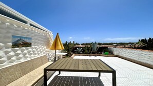 A patio with a wooden table and a yellow umbrella, surrounded by cacti and a white wall with a textured pattern. - Welooveyou Bellatrix Starlight B10 (Costa Calma (incl. Urbanización Cañada del Río))