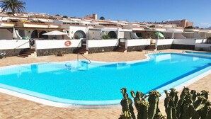 A swimming pool with a clear blue water, surrounded by a tiled deck. There are steps leading to a building with a white facade and a red-tiled roof. Cacti are visible in the foreground. - Welooveyou Bellatrix Starlight B10 (Costa Calma (incl. Urbanización Cañada del Río))