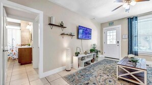 A living room with a television, a ceiling fan, a patterned rug, and a small table. - Cordova Palms - 4BR near Castillo w/ BBQ (St. Augustine)