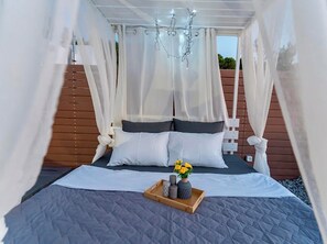 Une chambre à coucher avec un lit à baldaquin, une tête de lit en bois et une table de chevet sur laquelle se trouve un plateau avec divers objets.
