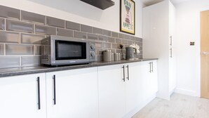 A modern kitchen with white cabinets, a grey microwave, and a tiled backsplash. - EXCLUSIVE MODERN NEWLY REFURBISHED HOME / CENTRAL LOCATION (Stoke-on-Trent)
