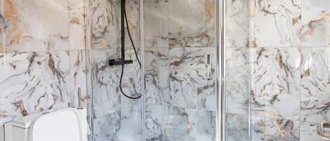 Un baño con cabina de ducha de vidrio, inodoro y paredes con diseño de mármol.