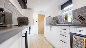 A modern kitchen with white cabinets, a toaster, a kettle, and a knife block. - EXCLUSIVE MODERN NEWLY REFURBISHED HOME / CENTRAL LOCATION (Stoke-on-Trent)