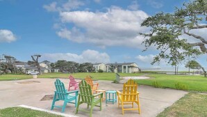 Un patio con sillas Adirondack y vistas a casas al fondo.