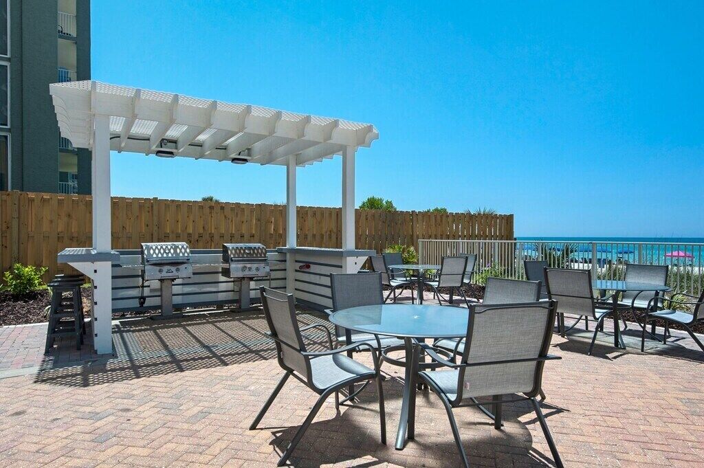 An outdoor patio with a grill, seating area, and a view of the ocean.