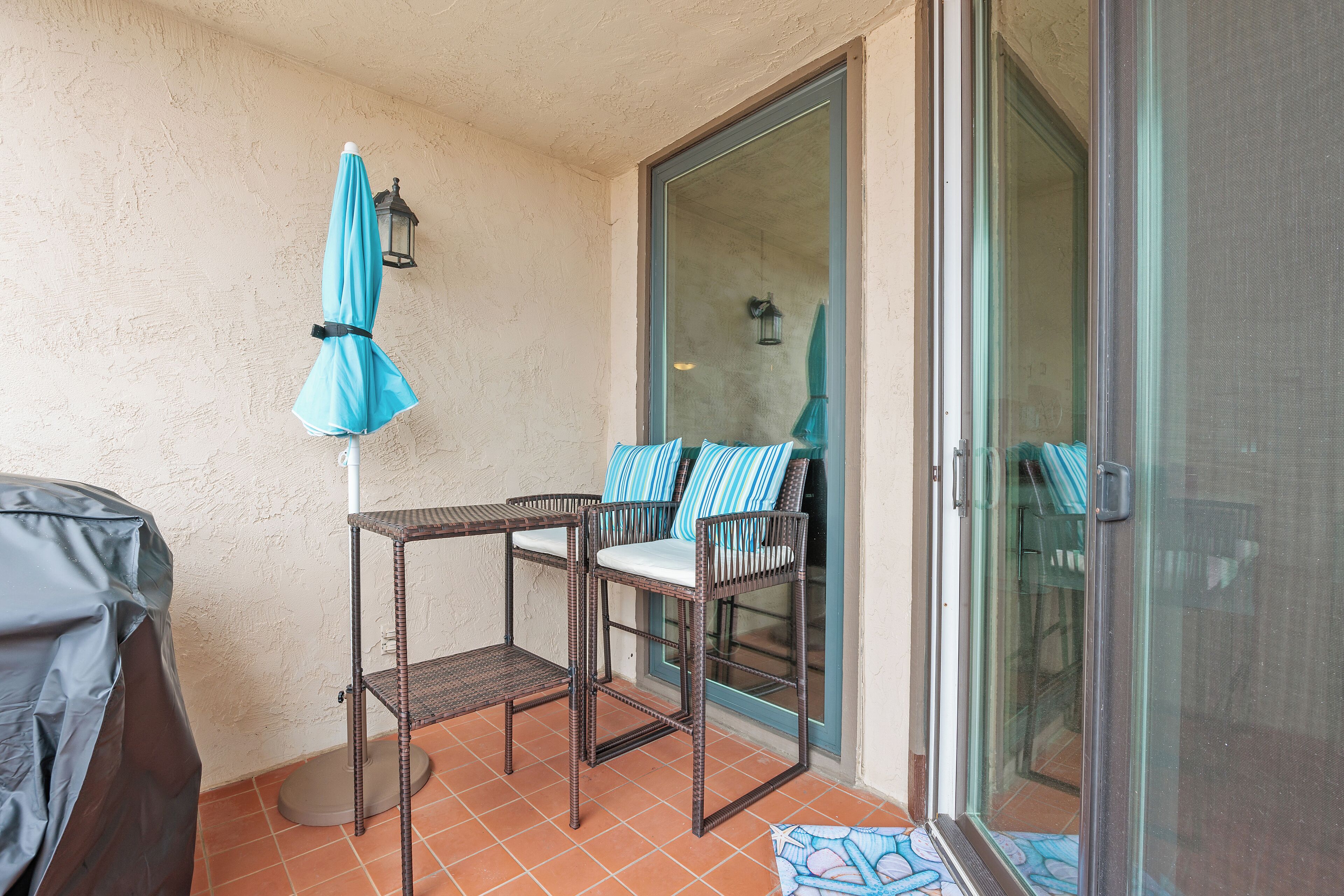 Un patio abrité, aménagé avec des meubles en osier, une table et des chaises.
