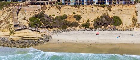 Un hôtel situé sur la côte, avec une falaise rocheuse, une plage de sable et une vue dégagée sur l’océan.