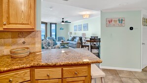 A kitchen with granite countertops, wooden cabinets, and a dining area with a table and chairs.