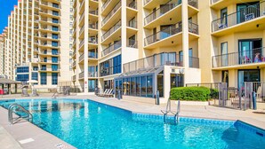 A swimming pool with a glass enclosure, surrounded by multi-story residential buildings with balconies.