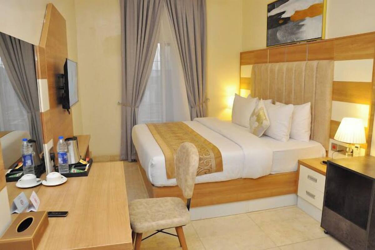 Een hotelkamer met een bed, nachtkastje, stoel, bureau en een televisie.