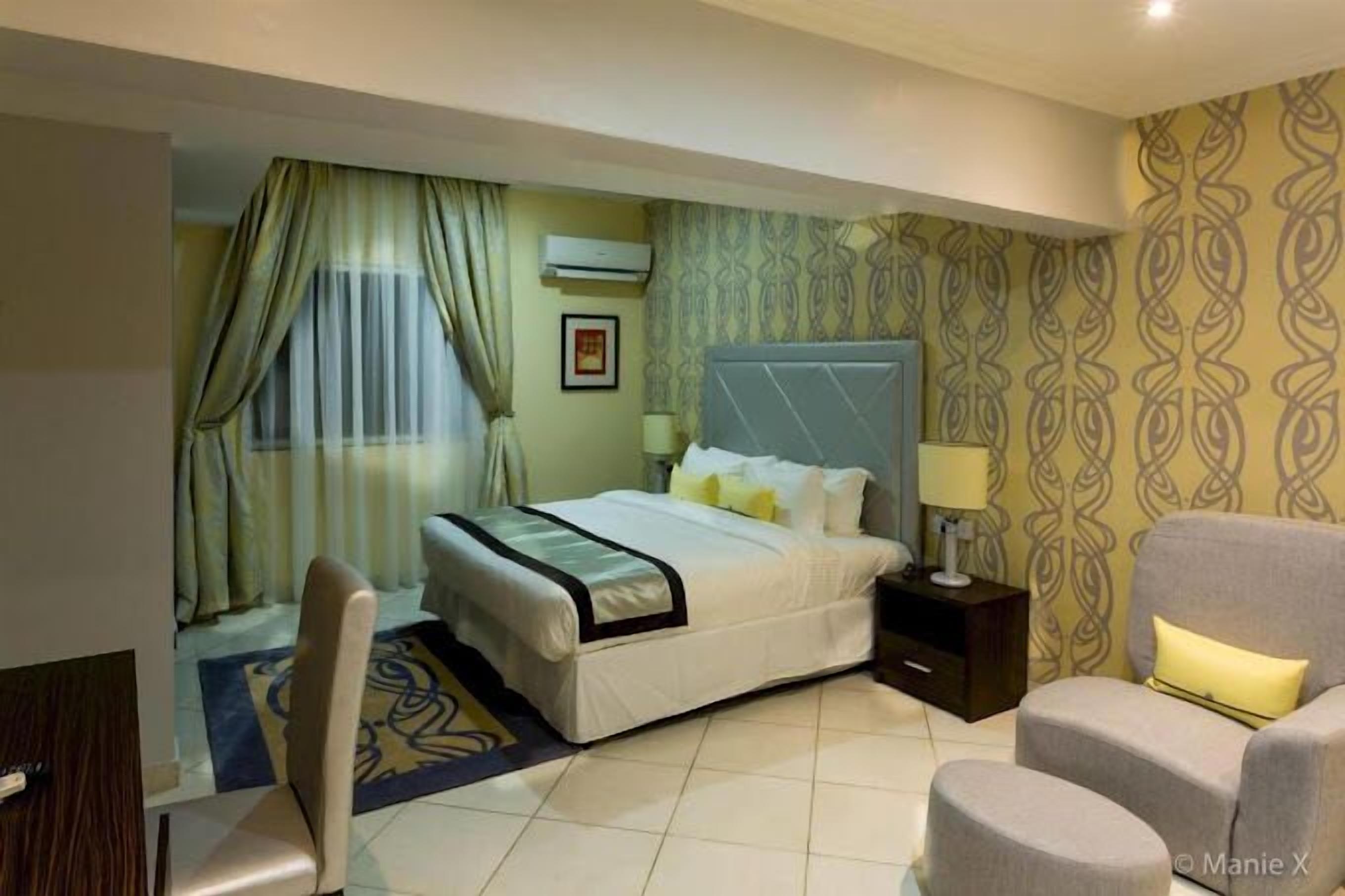 Een hotelkamer met een bed, nachtkastje, stoel en een bank.