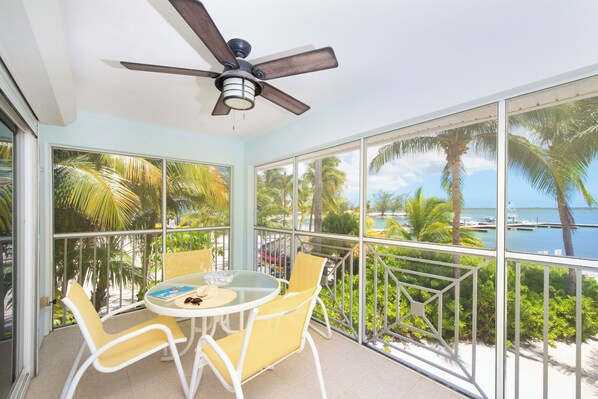 A balcony with a glass door, a ceiling fan, and a table with chairs.