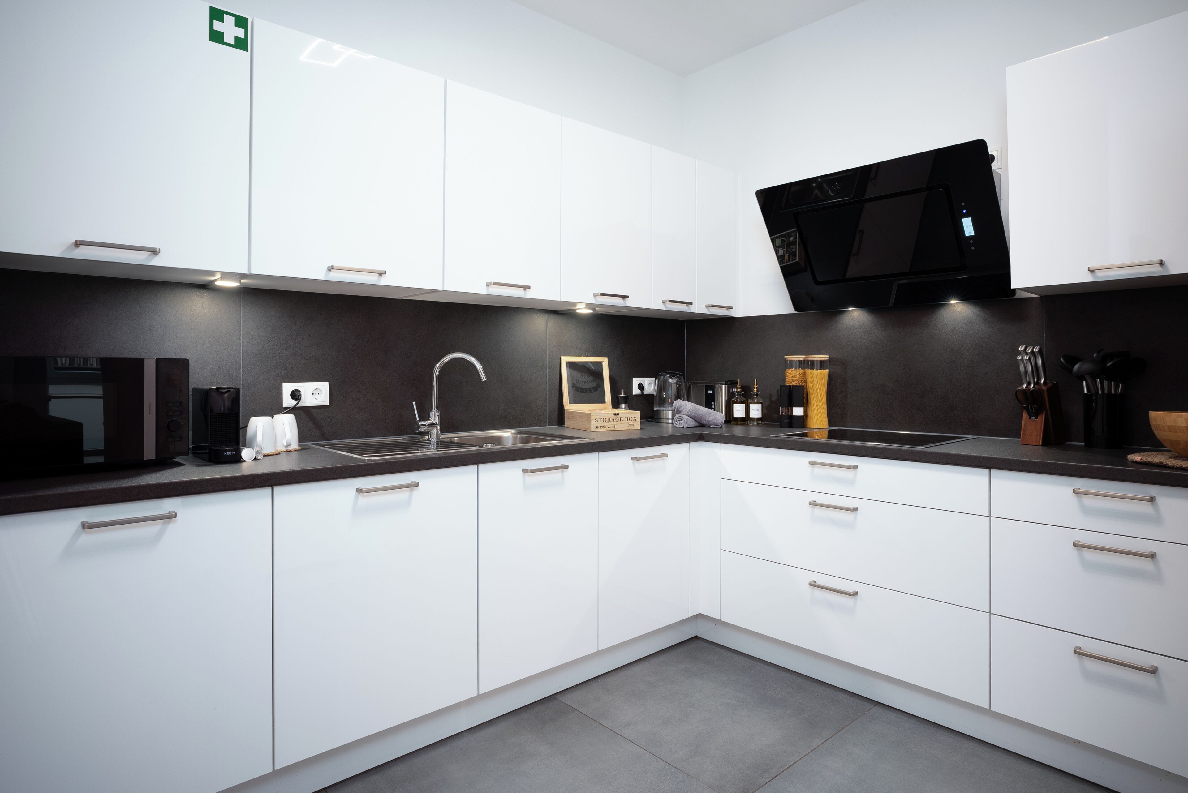 A modern kitchen with white cabinets, a black countertop, and a built-in oven.