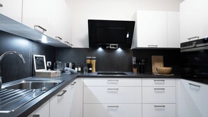 Cozinha moderna com bancada preta, armários brancos e forno embutido.