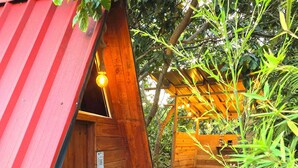 Une cabane en bois avec un toit en pente, une porte dotée d’une poignée et un paillasson sur lequel est inscrit le mot « BIENVENIDO ».