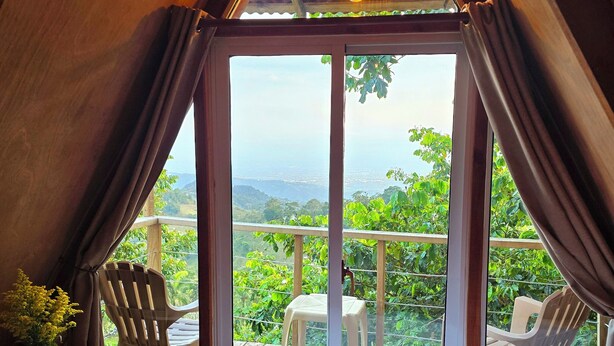 Une pièce chaleureuse avec une grande fenêtre, un plafond en bois et une vue sur la verdure environnante.