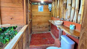 Une petite salle de bain en bois comprenant des toilettes, un lavabo et une petite fenêtre.