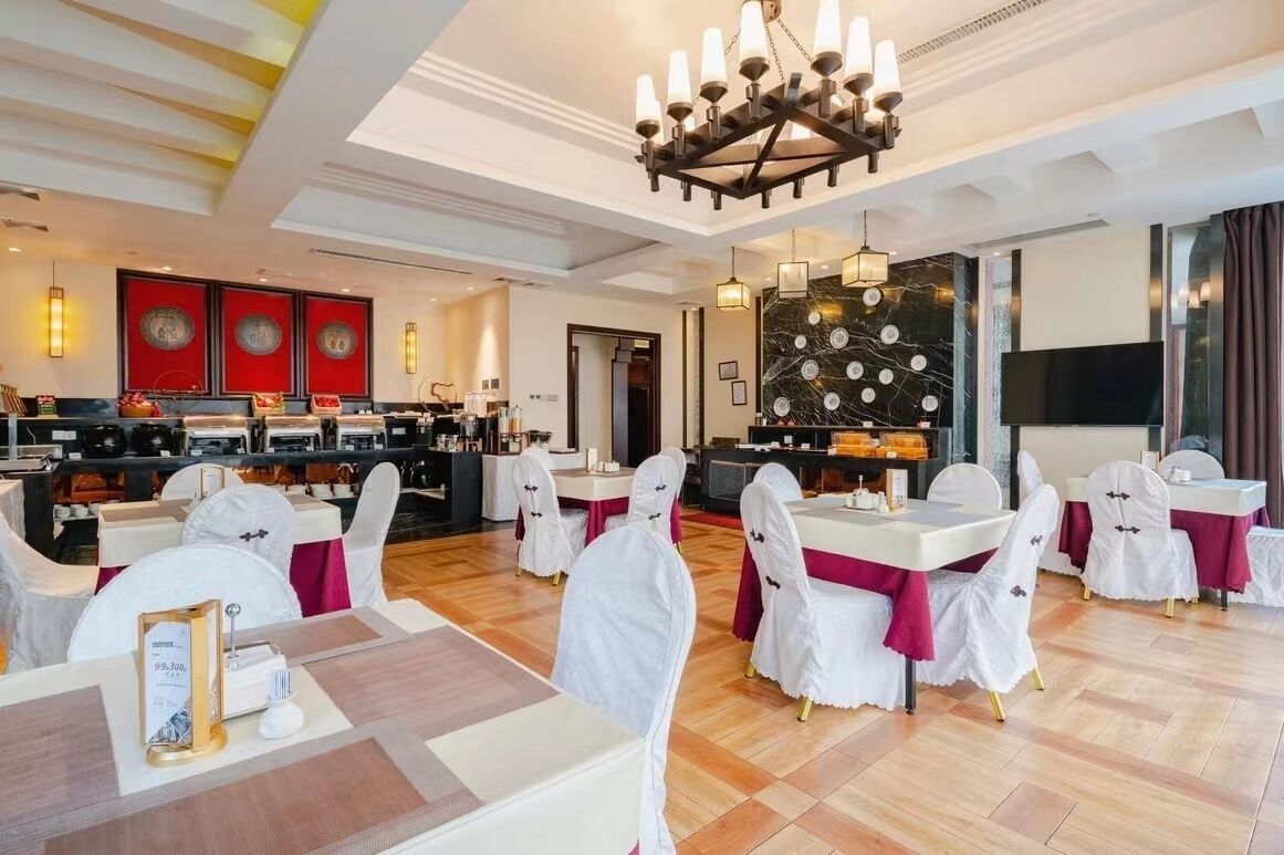 A hotel dining area with tables set for guests, a bar area, and a large screen TV.