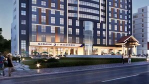 A modern hotel with multiple floors, a prominent entrance with a glass facade, and a visible bank branch.