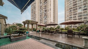 A rooftop patio with outdoor seating and a view of high-rise buildings.
