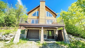 Ein zweistöckiges Haus mit Garage, Balkon und Natursteinfundament.