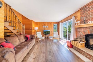 A wooden interior with a sofa, chairs, a fireplace, and a TV.