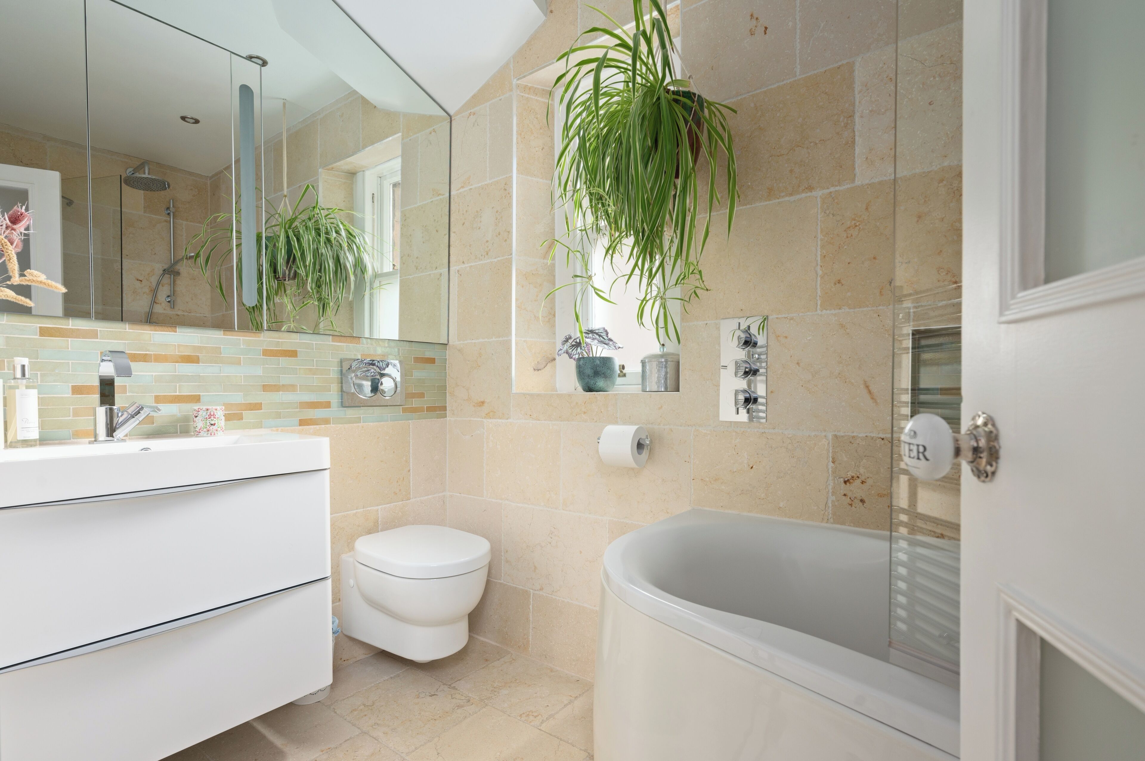 A modern bathroom with a white vanity, a toilet, a bathtub, and a large mirror.