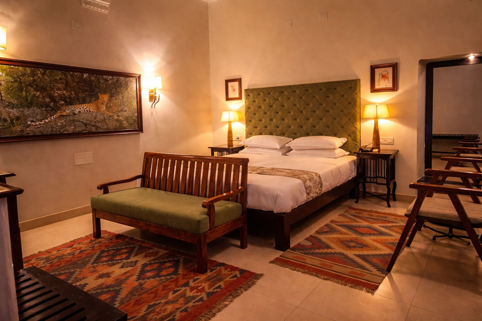 A bedroom with a bed, a wooden chair, a patterned rug, and wall-mounted lamps.