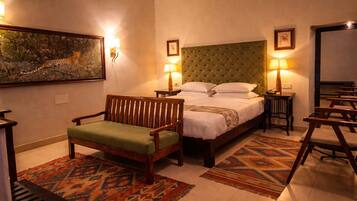 A bedroom with a bed, a wooden chair, a patterned rug, and wall-mounted lamps.