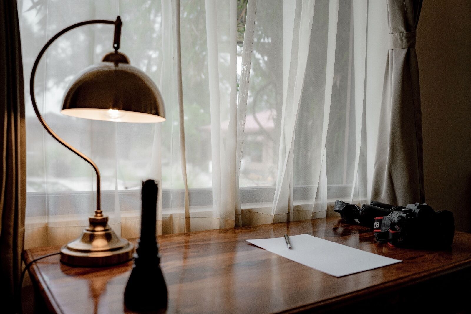 Una scrivania con una lampada, una bottiglia e una macchina fotografica.