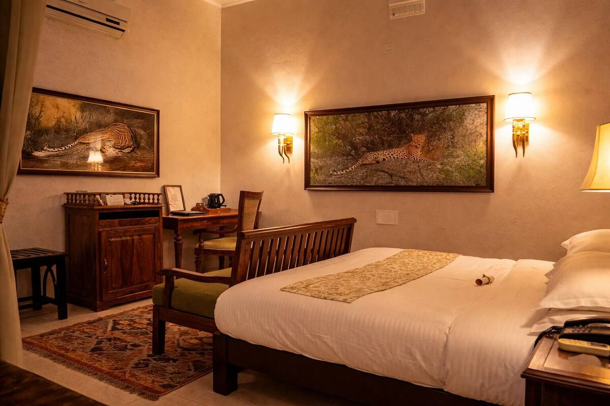 Ein Hotelzimmer mit einem Bett, einem Schreibtisch, zwei Wandleuchten und zwei gerahmten Bildern.