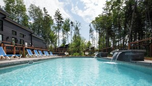 A swimming pool with lounge chairs, a waterfall feature, and a building with a dark facade.
