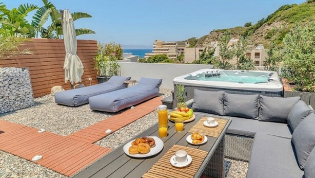 A rooftop terrace with a hot tub, lounge chairs, and a table set with breakfast. - Sunny Nest Apartment 2 in Ixia (Ialisos)