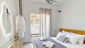 A hotel room with a bed, a mirror, a bathroom with a sink, and a view of the outdoors. - Sunny Nest Apartment 2 in Ixia (Ialisos)