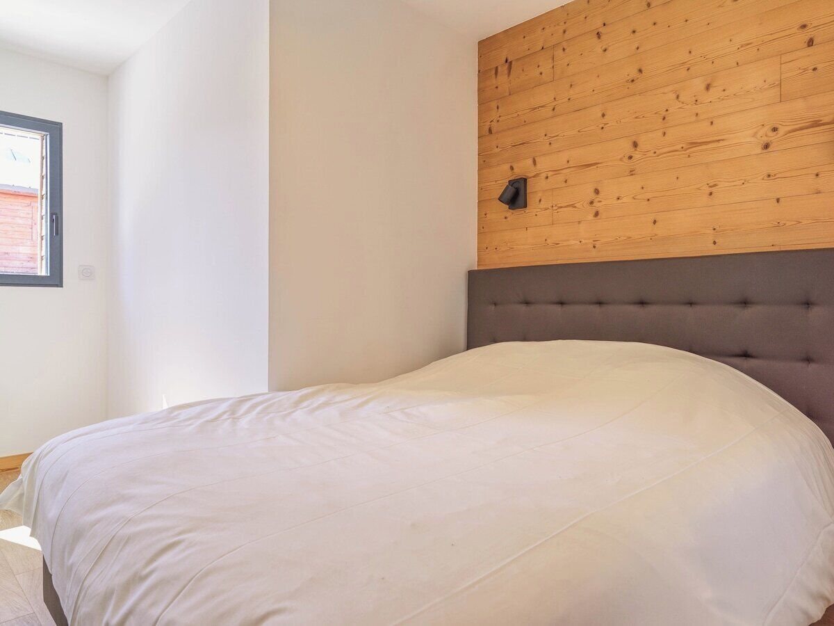 Een slaapkamer met een bed, een houten hoofdbord en een raam.