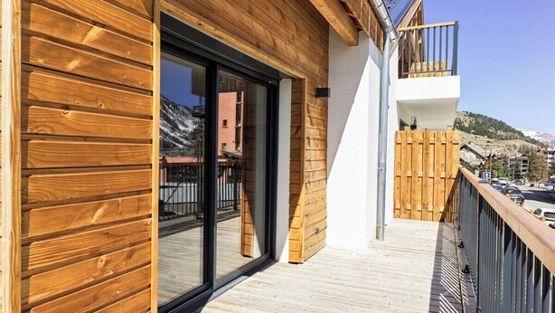 A wooden exterior with a glass door, a balcony, and a view of a mountainous landscape. - Apartment Le Cozy, high-end newly constructed! (Montgenèvre)