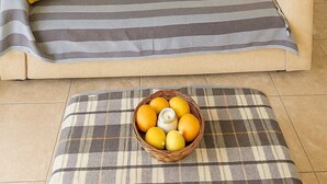 Zona d'estar acollidora amb sofà, almoinades i una taula amb un cistell d'albercocs.