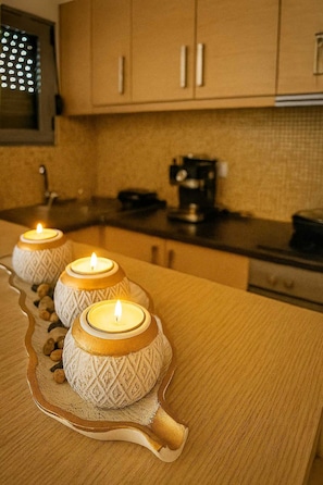 A kitchen with three decorative candles on a tray, wooden cabinets, and a coffee maker on the counter.