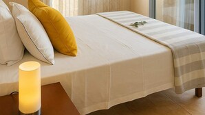 Habitació d'hotel amb un llit, una taula de nit amb una làmpada, una finestra amb cortines i vista a l'exterior.