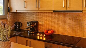 Una cuina moderna amb armaris de fusta, un taulell negre, una cafetera i un bol ple de taronges.