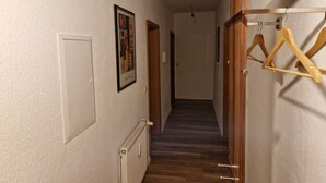 A hallway with a wooden floor, a radiator, a door, and a coat rack.