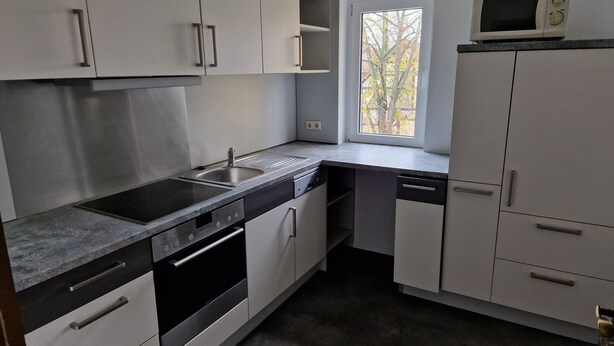 A compact kitchen with a sink, stove, and microwave.